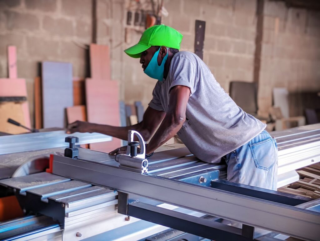 A skilled African woodworker focused on operating machinery in a workshop in Kaduna, Nigeria.