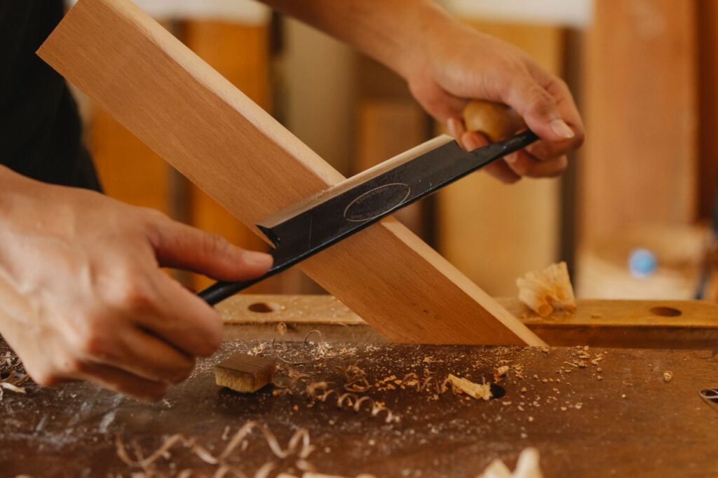 Faceless joiner cutting hardwood plank with sharp manual tool at workbench in studio