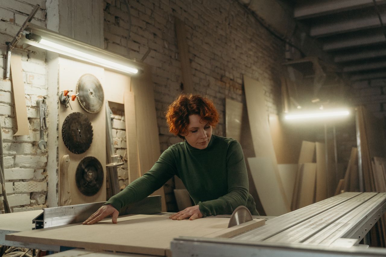 Mastering the First Impression: Your intriguing post title goes here A focused woman working with a circular saw in a woodworking workshop.